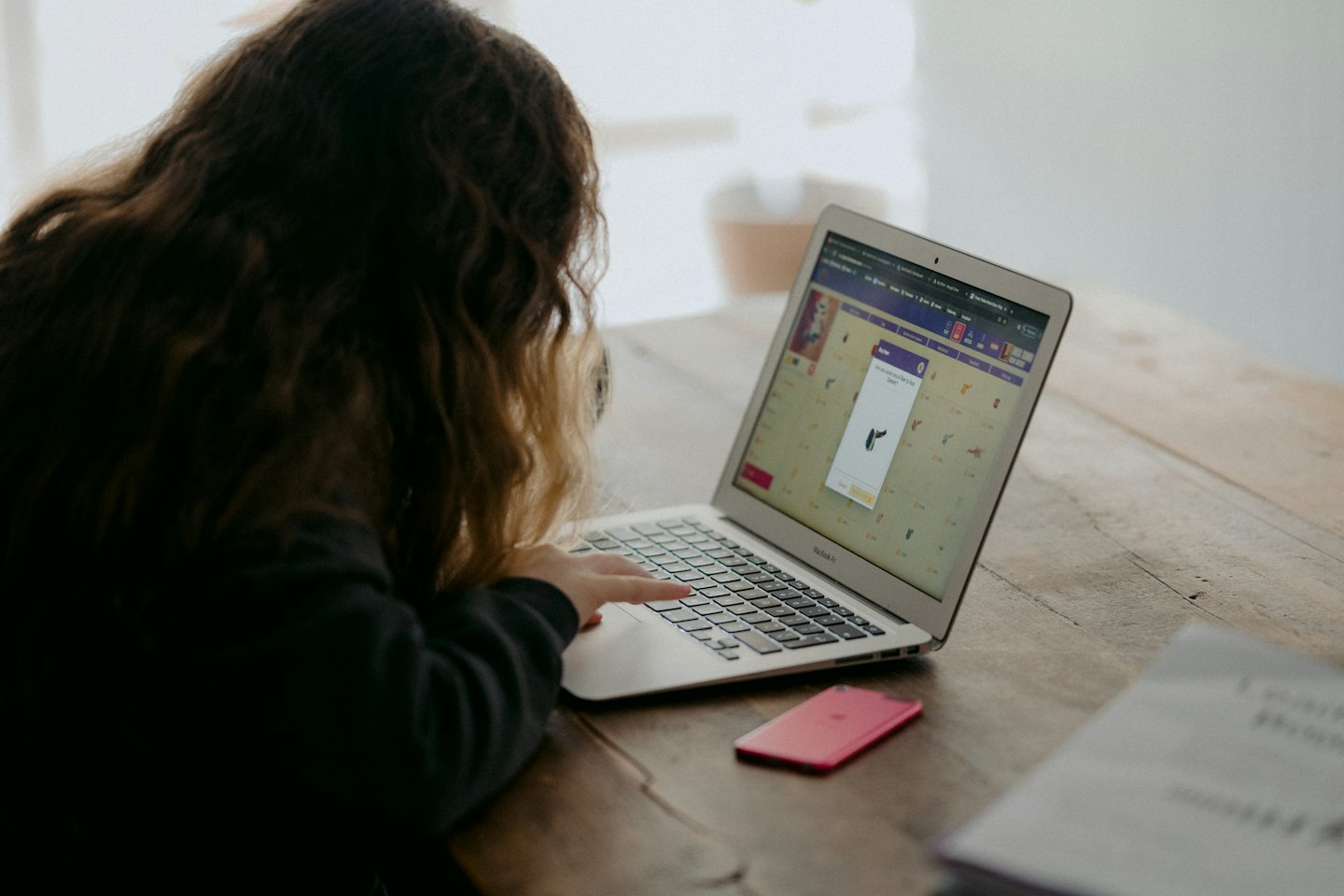 Person typing on a laptop with product listings on screen.