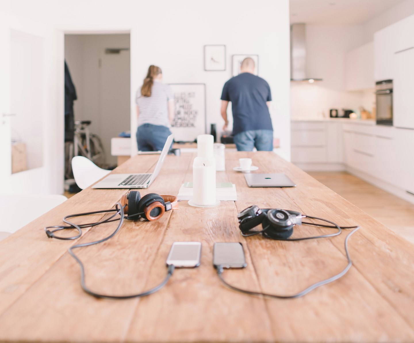 Laptops, phones, and headphones on a shared workspace table.