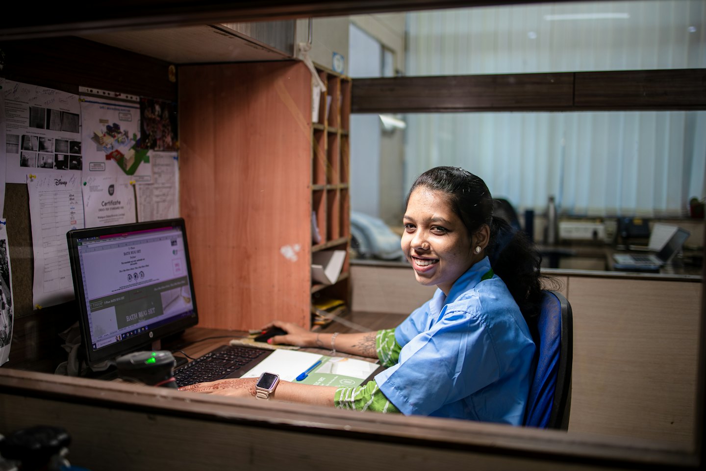 Woman in blue uniform working at her office computer.